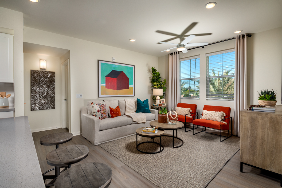 2 BR Apartments in Riverside, CA - The Hawthorne - Living Room with Large Window Orange Chairs, Grey Couch, Area Rug, and Coffee Table.